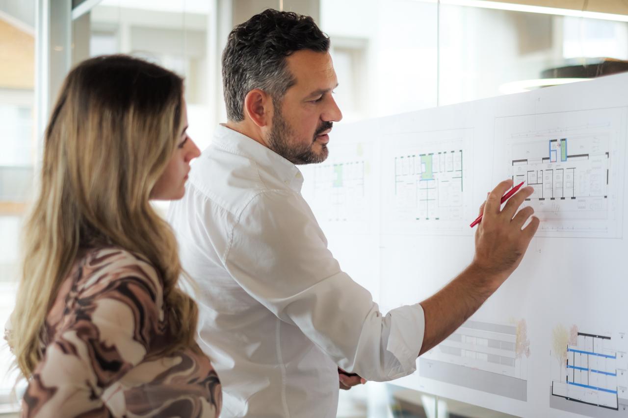 Nefail Ademi and Vildane Shetifi pointing to an architectural sketch.